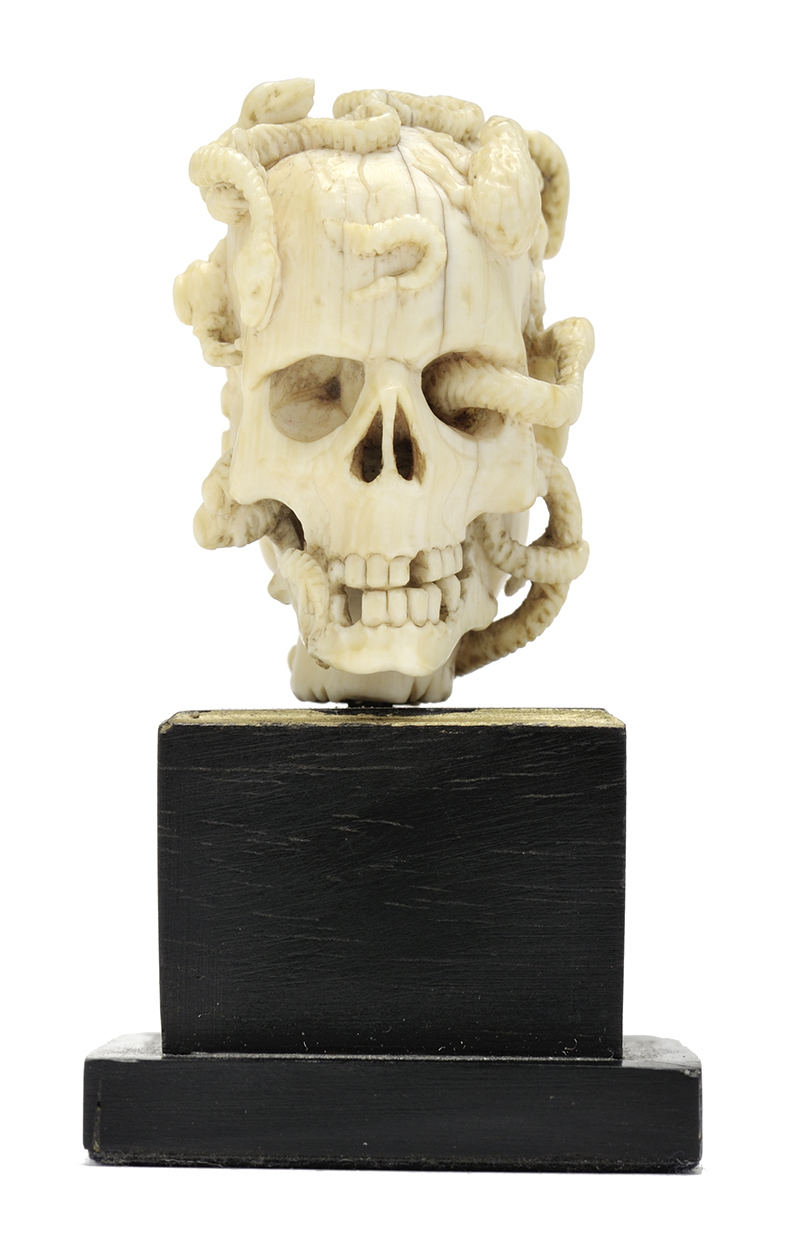 A small ivory sculpture of a human skull we snakes
