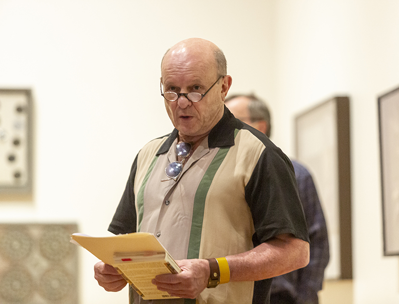 A man standing in an art gallery, with papers in his hands