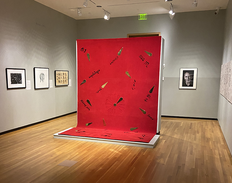 A bright red rug with ornaments installed in an art gallery