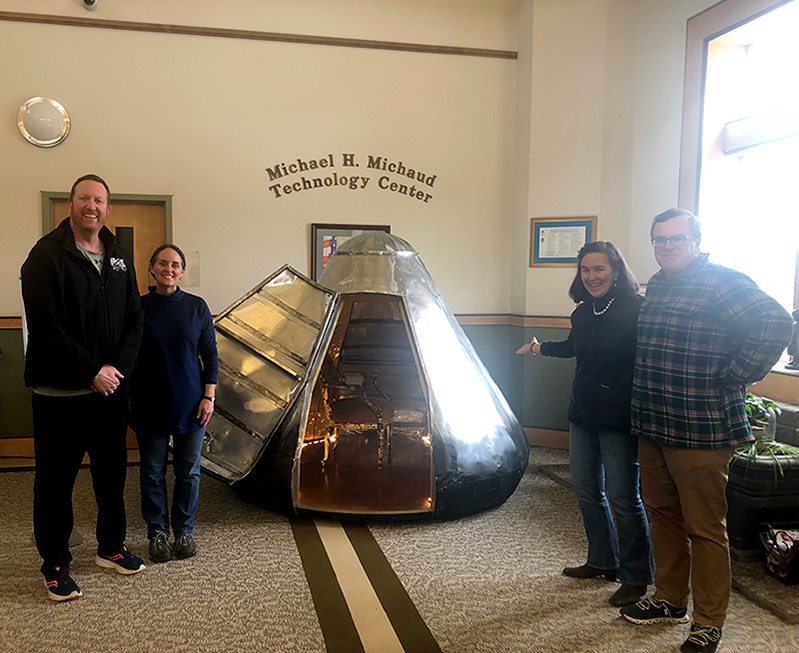 An sculpture in the shape of a lunar capsule is surrounded by onlookders