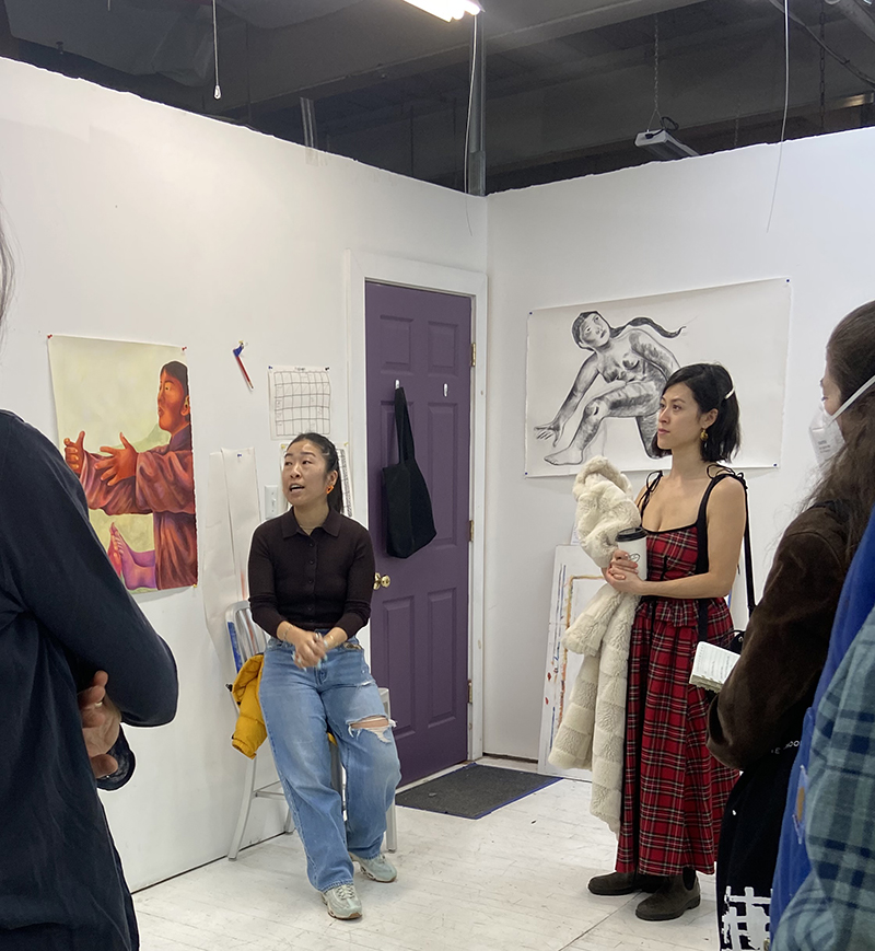 Last month, Museum staff and members of the Collectors’ Collaborative visited artist Lily Wong at her studio in Greenpoint, Brooklyn. Established in 2007 and co-chaired by Isabel Taube ’92 and Ellen Grenley McKernan ’06, the Collectors’ Collaborative offers Bowdoin graduates pathways to stay connected with one another, the Museum, and the visual arts through twice-yearly excursions. During these events, Collaborative members hear directly from artists about their practice and often see material that has not yet been displayed publicly. Over two dozen alumni, ranging from the class of 1988 to 2022, gathered last month to join a stimulating discussion with Wong about her current work and upcoming projects. A native of Seattle, Lily Wong is a figurative painter whose work explores themes of yearning, intimacy, and memory through the juxtaposition of bodies in space and time. Wong spoke about her training and background, sharing insights about her journey transitioning from printmaking to painting, monochrome to color, and small- to large-scale work. She also shared examples from an ongoing series that explores, among many things, her recent foray into traditional Chinese medicine. Drawn to Eastern medicine’s holistic approach to the body, Wong aims to represent the interconnectivity between mind, spirit, and the environment as her figures meander across dream-like landscapes and urban structures. Her other influences range from Hong Kong cinema to Japanese animation. This and other events are jointly organized by Museum staff and the Collaborative’s co-chairs and programming committee, who meet regularly to discuss upcoming opportunities and to share artists and topics of interest. The visit to Wong’s studio arose from conversations about the current exhibition Without Apology: Asian American Selves, Memories, Futures, which was curated by five Bowdoin faculty members as part of the College-wide Asian American Reckonings initiative. This project prompted the Museum to expand its holdings of work by artists of the Asian diaspora, and Collaborative members eagerly shared a long list of Asian American artists that they were interested in learning more about. We are grateful to this group for introducing us to Lily Wong and orchestrating such a fun and engaging afternoon at her studio. By sharing their art-world connections and ideas, Collaborative members directly shape the Museum’s collections. Members who contribute to a designated acquisitions fund are given the opportunity to vote on a work of art featured at one of the year’s Collaborative events. The winning artwork is then purchased by the Museum using the donated funds, ensuring the interests of Bowdoin alumni are reflected in the collection and future exhibitions. With no set minimum contribution, members can donate any amount, which helps guarantee an inclusive process. However, members do not need to donate in order participate in events, which are open to all Bowdoin alumni. To learn more about how to be involved with the Collectors’ Collaborative, we invite you to reach out to CollectorsCollaborative@bowdoin.edu. We will add you to the Collaborative mailing list to learn more about upcoming events. We are thankful for co-chairs Isabel and Ellen, as well as our current Collaborative members, for their commitment to championing the arts at Bowdoin College and beyond. Cassandra Braun, Curator Bowdoin College Museum of Art