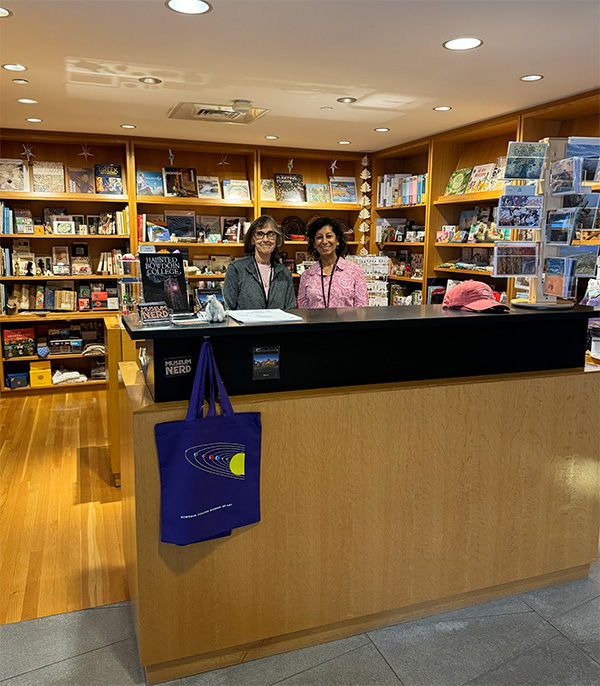 Two people smile standing behind a counter at a museum gift shop