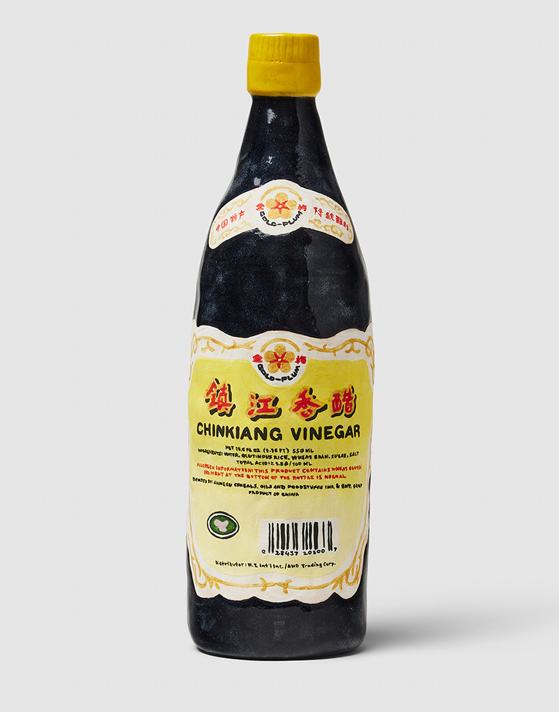 A painted, ceramic sculpture shaped like a vinegara bottle