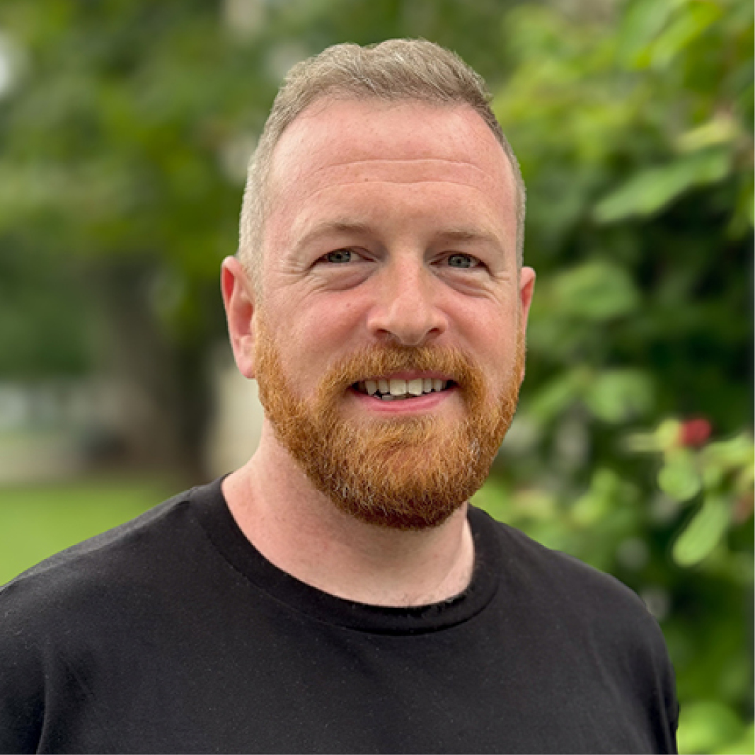A headshot of a person in a black t-shirt