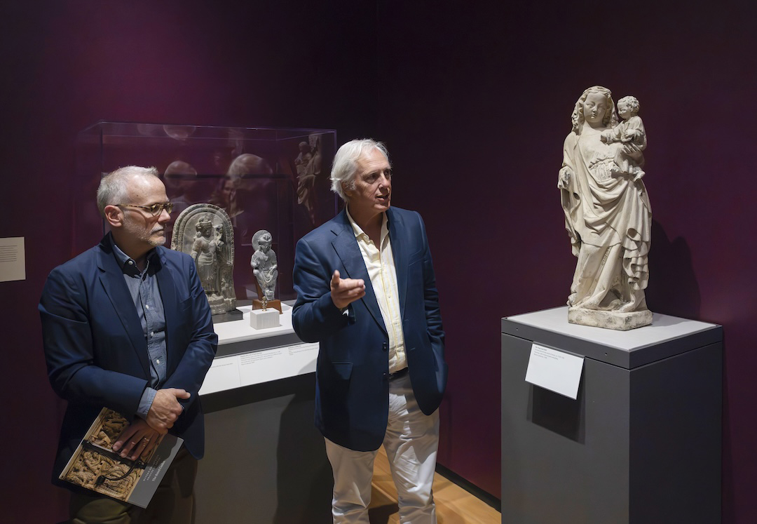 Two people give a tour of an exhibition of medieval art