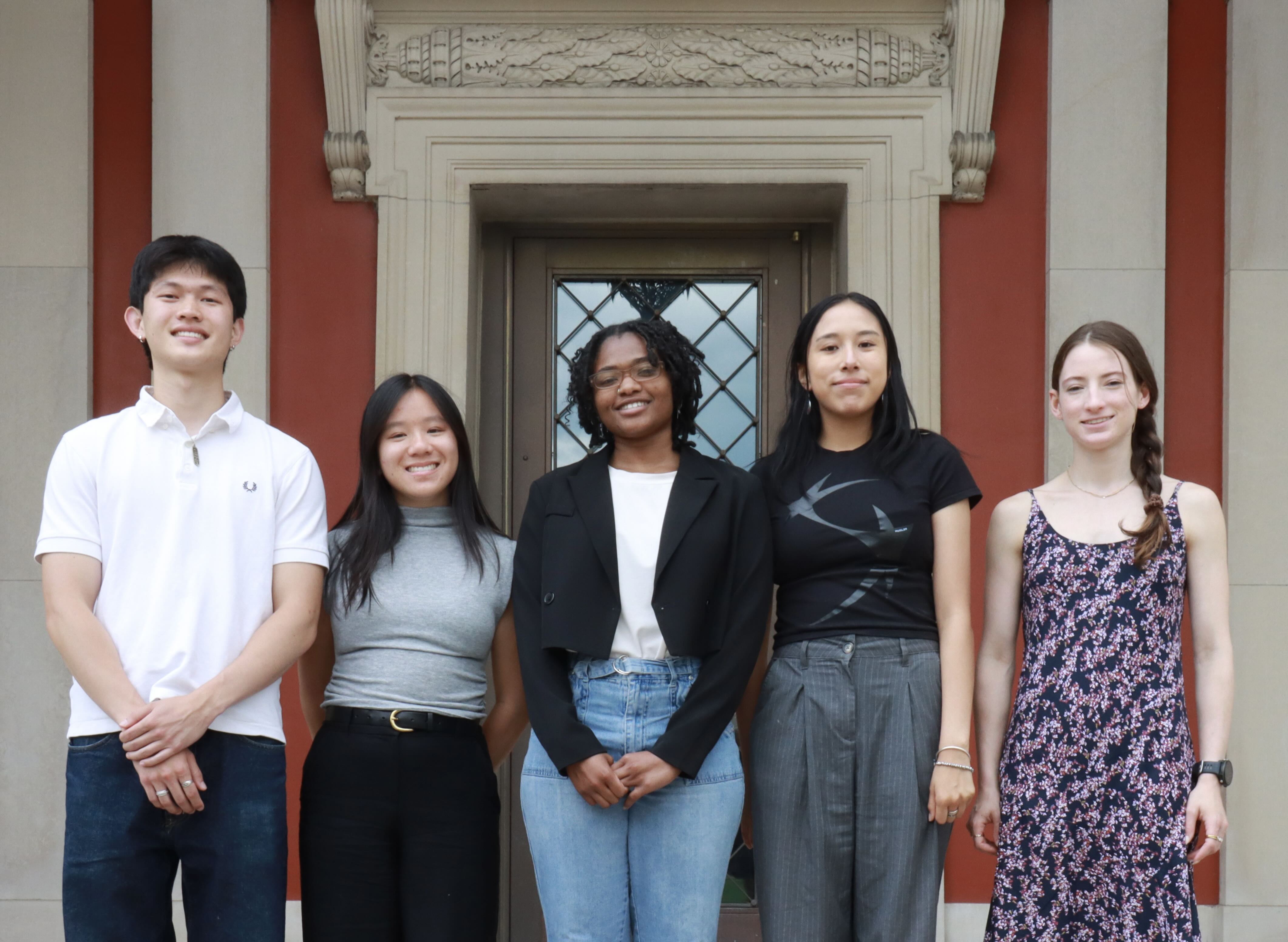 Five student interns stand in front of an art museum exterior