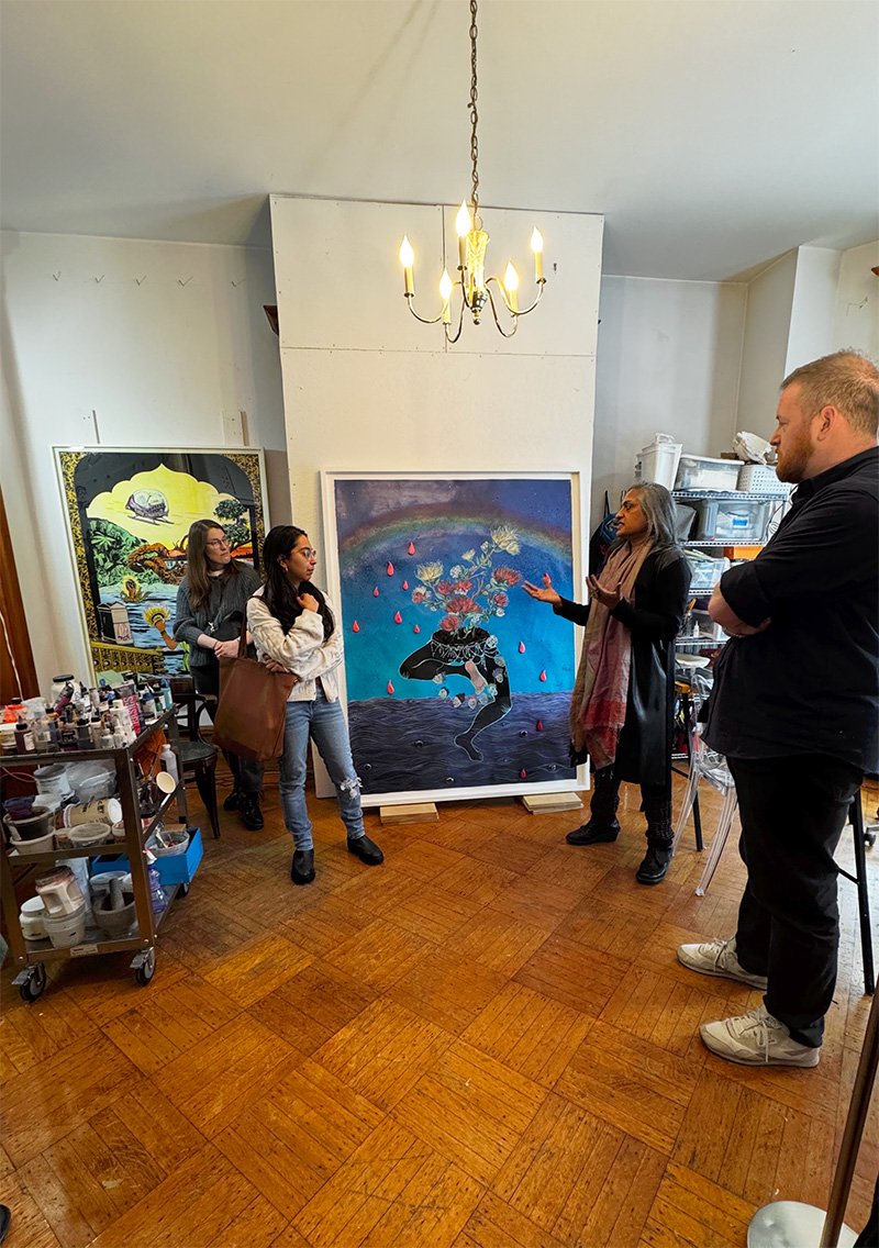 People gather in an artist's studio to look at colorful artwork