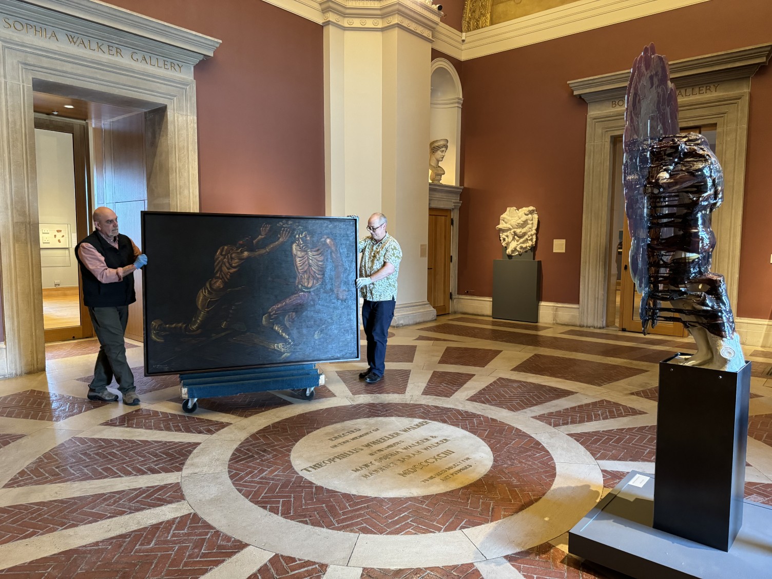 A large painting is moved into a gallery for installation