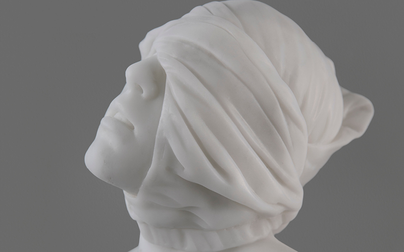 A detail of a marble sculpture depicting a male figure with his eyes obscured