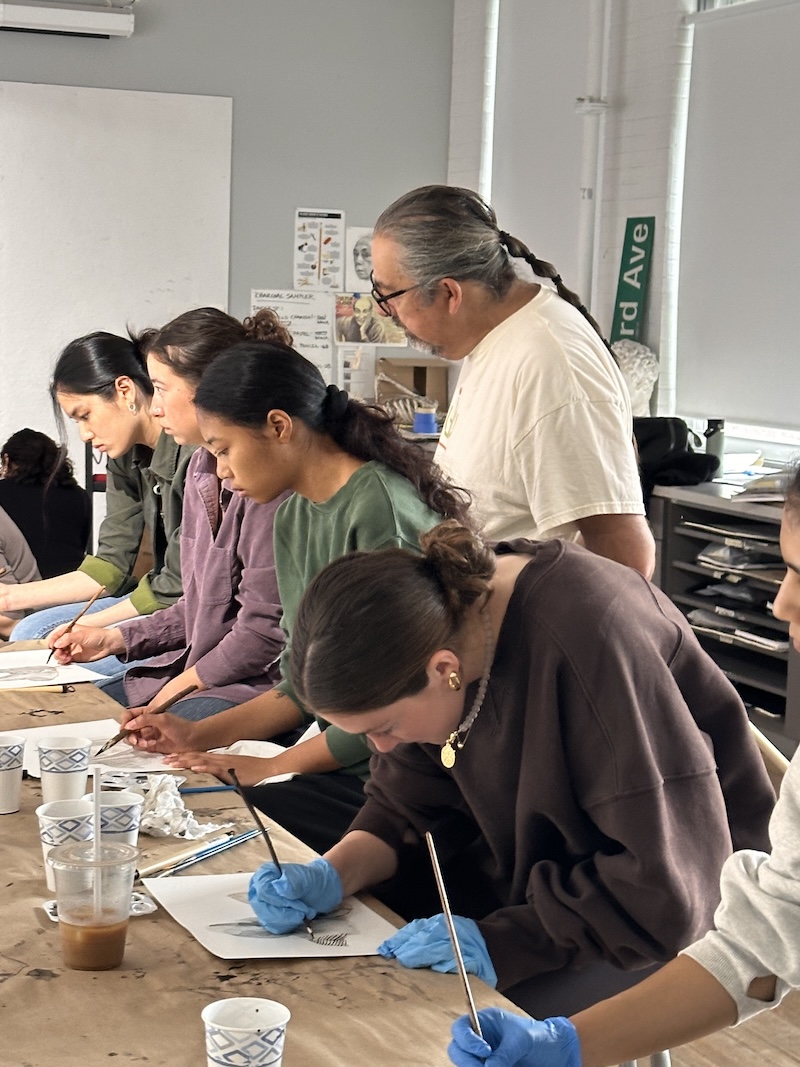 An artist guides students in a college art class