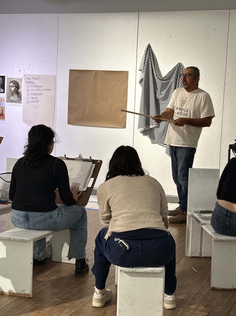 An artist guides students in a college art class