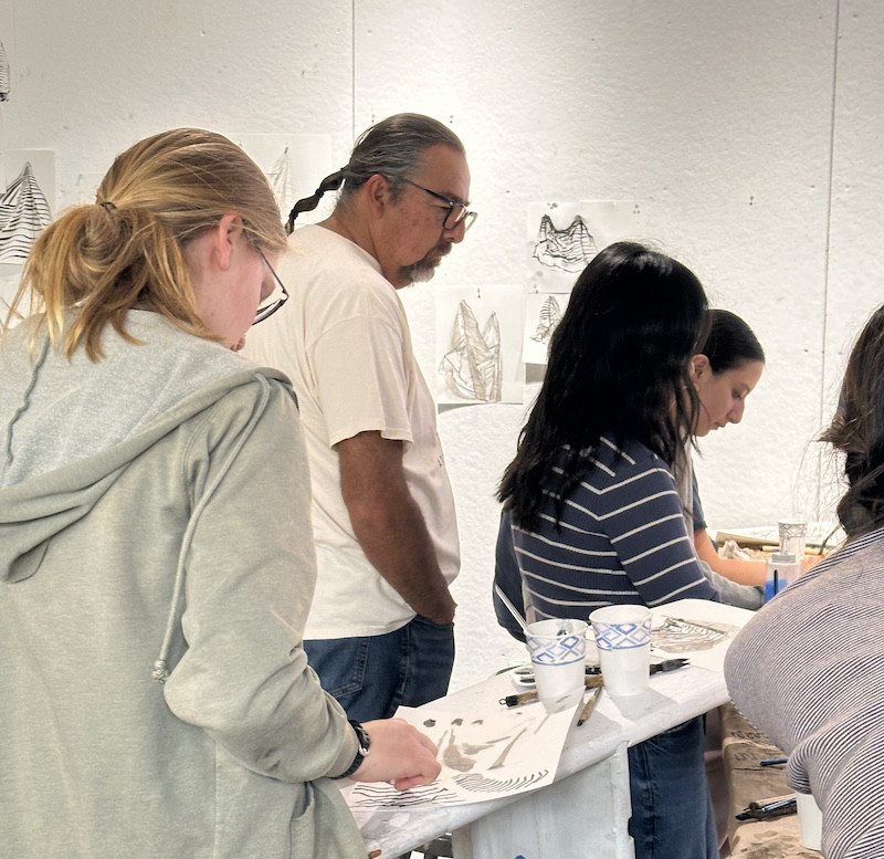 An artist guides students in a college art class