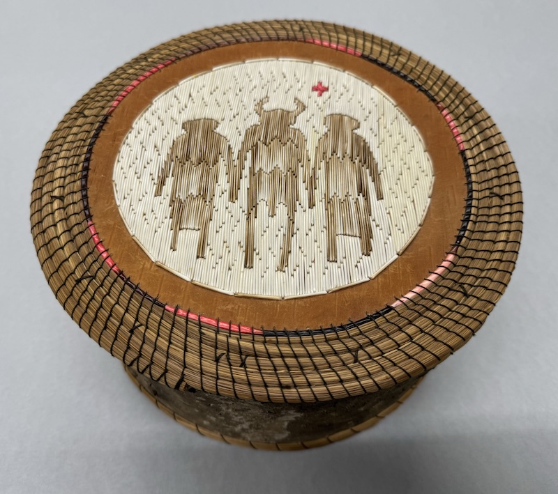 A traditional Indigenous basket with depictions of three figures