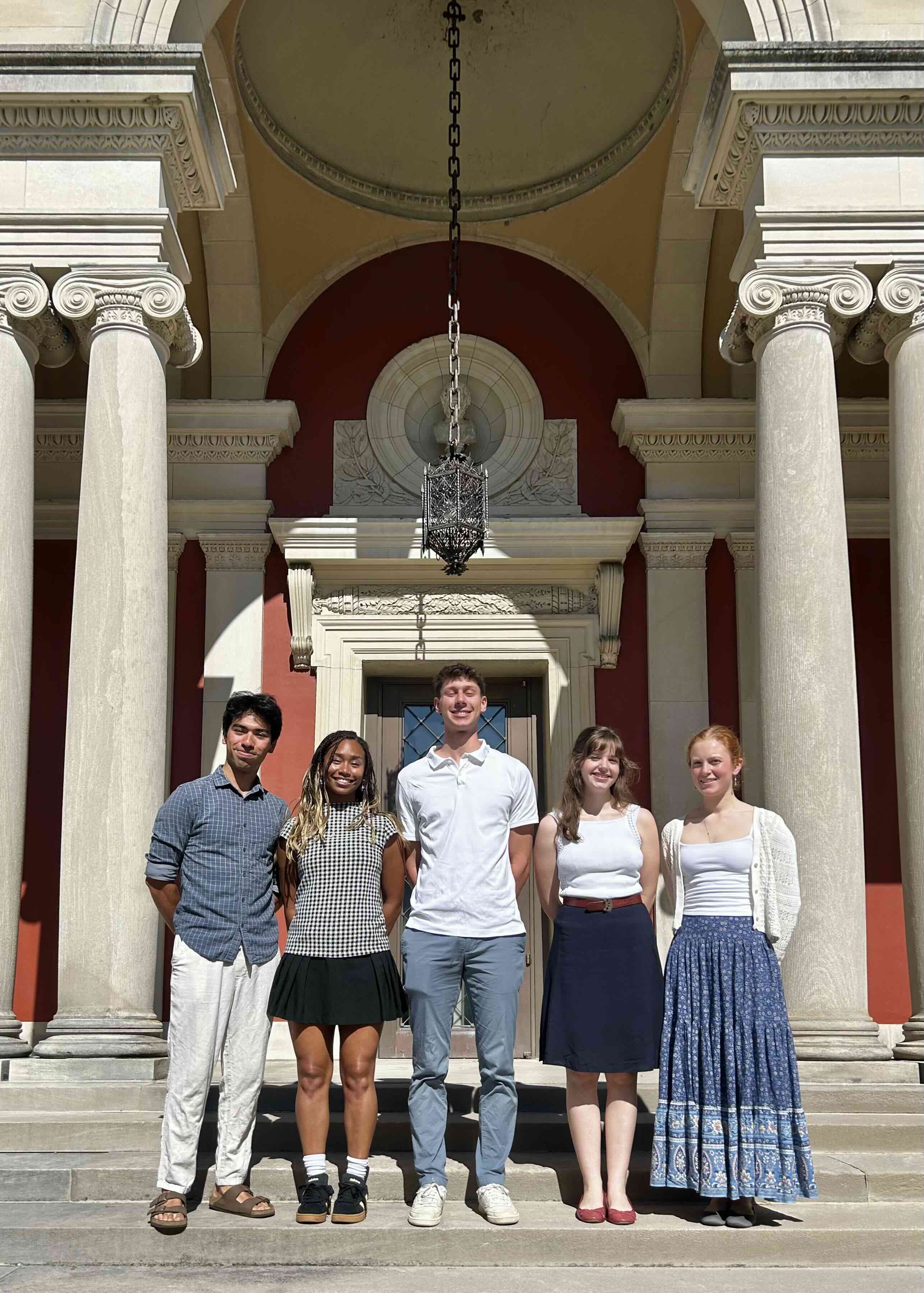 Five student interns pose in front of an art museum