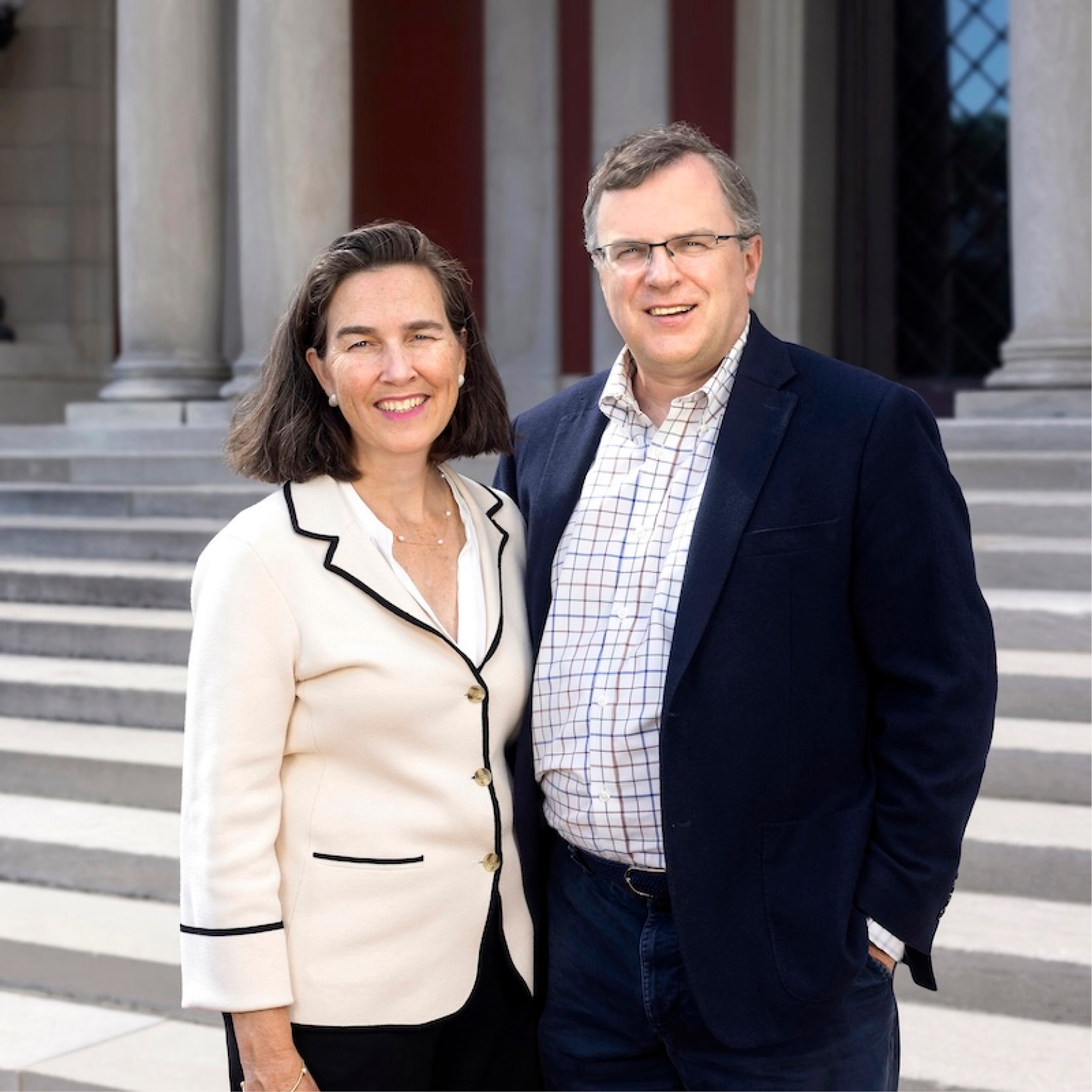 Two people stand smiling in front of an art museum