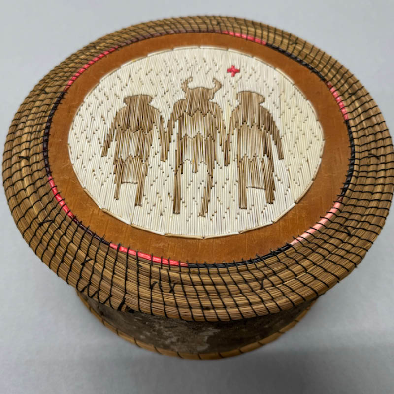 A traditional Indigenous basket with depictions of three figures