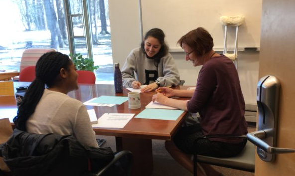 Photo of Lisa Flanagan working with two students at a table in the Baldwin Center library