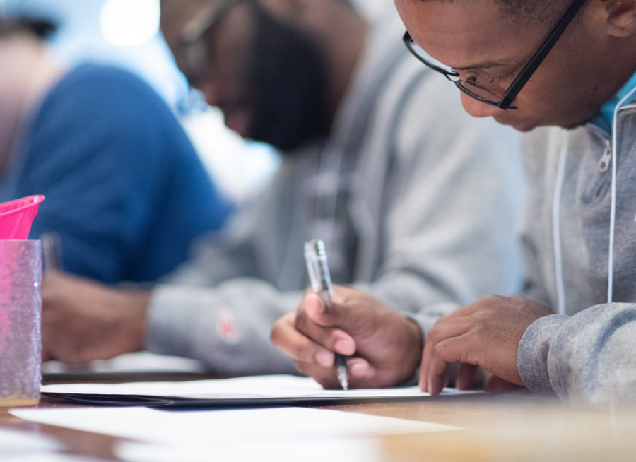 Student writing with a pen in Thorne Dining Hall