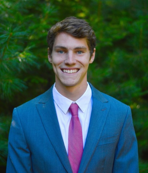 male student smiling wearing a blue suit