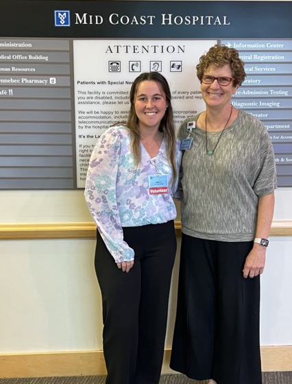 Abby poses with a co-worker in front of Mid Coast Hospital's sign.