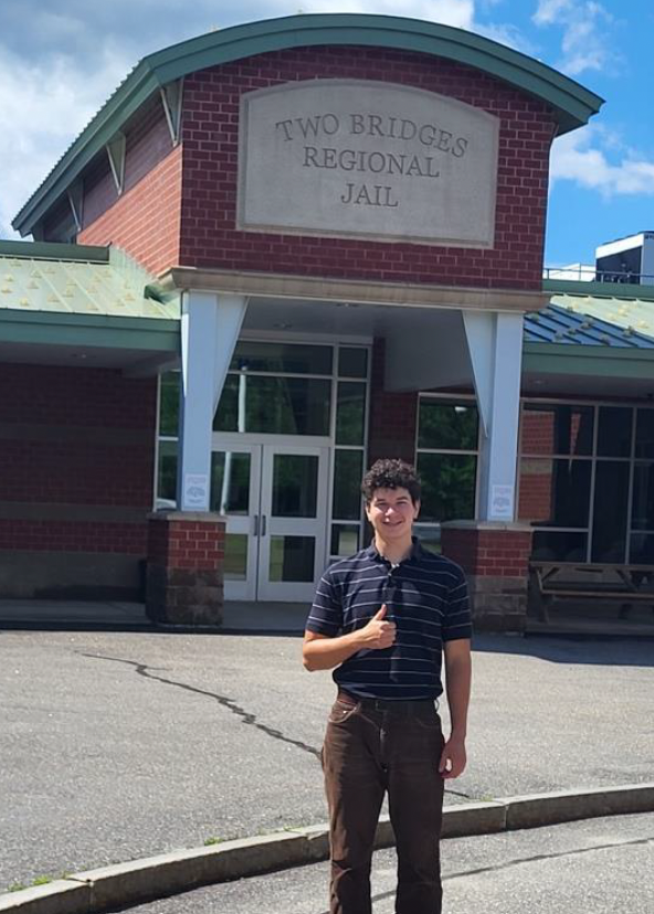 Adam poses in front of Two Bridges Jail in Wiscasset.