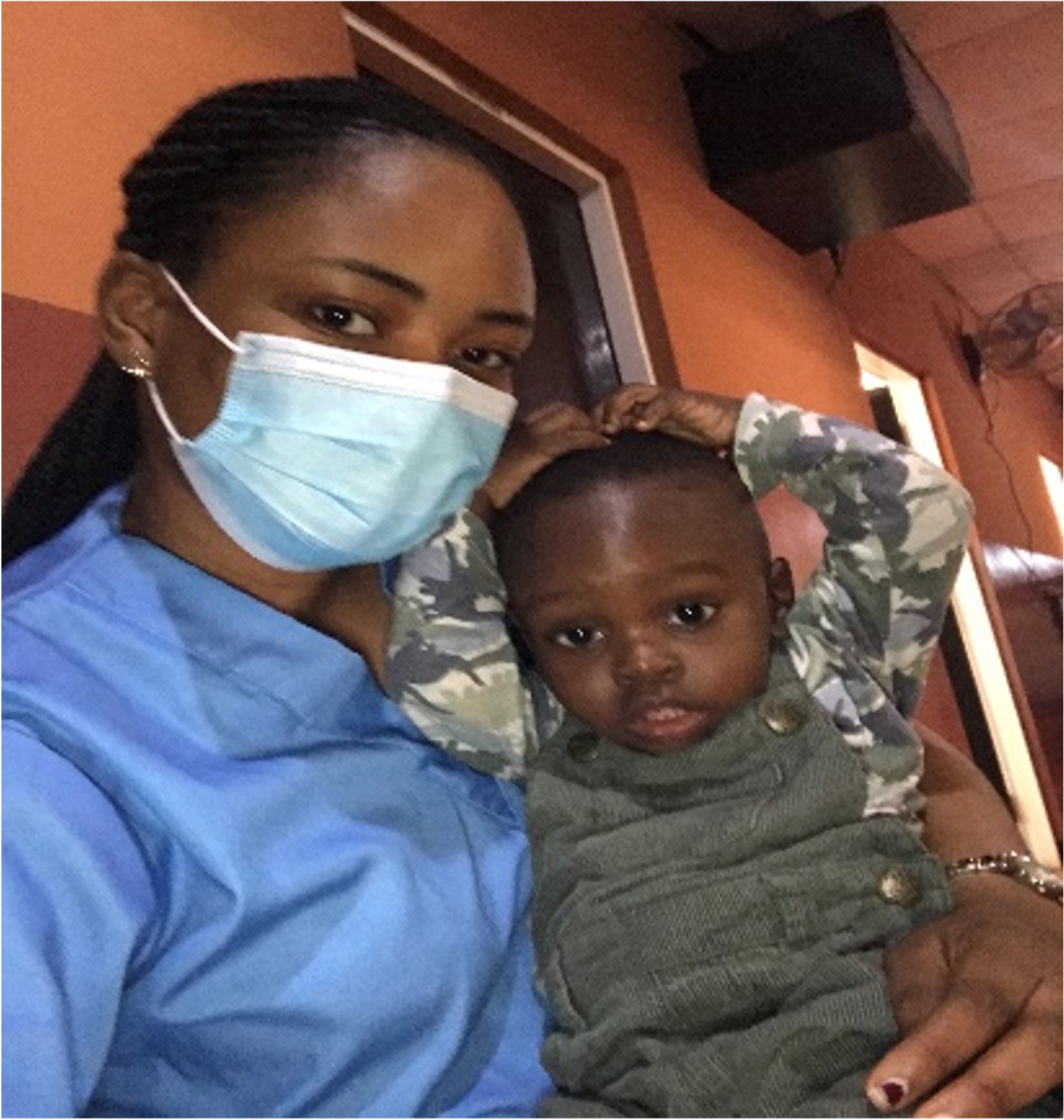 adedunmola in scrubs holding child
