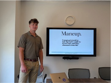 Andrew Szwez standing in front of screen that says Maneup