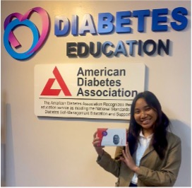 Brigit Len Tabuena stands in front of sign that days "Diabetes Education"
