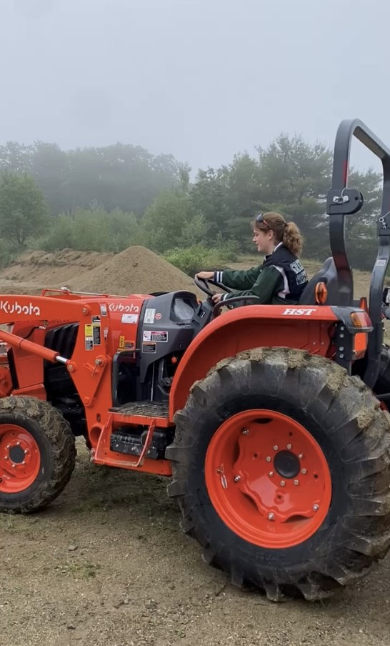 Chloë operates a tractor across a field.