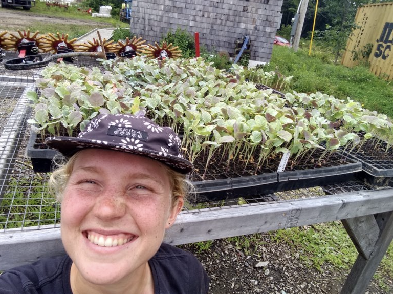 Emma smiles for the camera while posing in front of a garden.