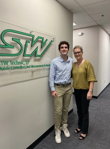 Grady poses with coworker in front of STW Technic sign. 