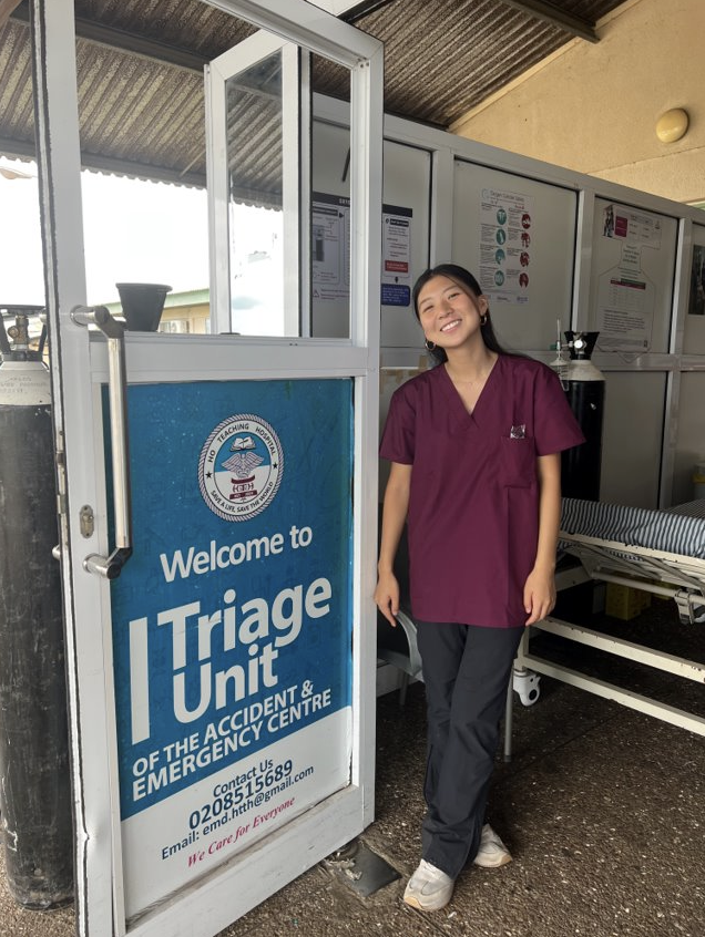 Hanna poses with scrubs next to Triage Unit sign.