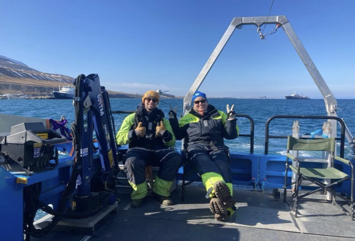 Jondall poses with a team member while on a boat out at sea.