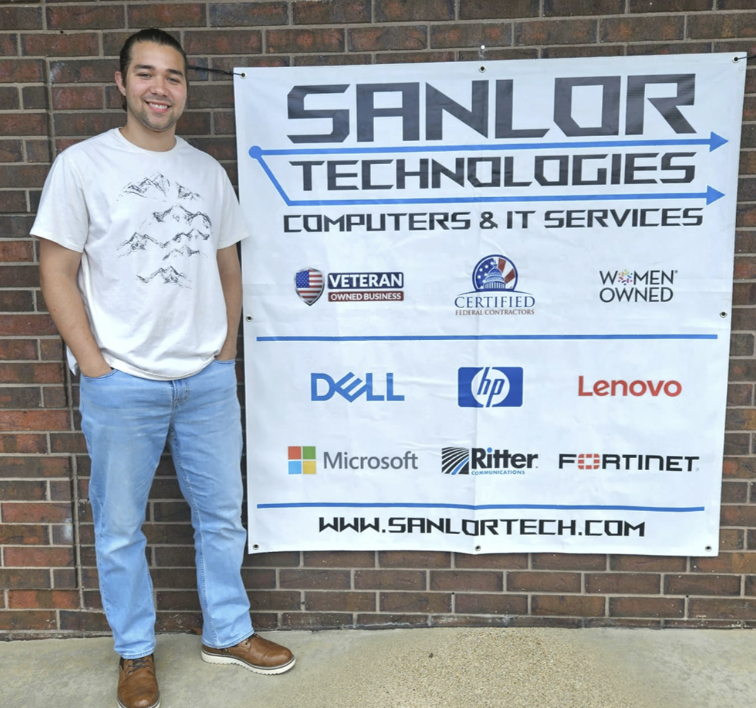 Kenny poses next to SANLOR Technologies' sign.