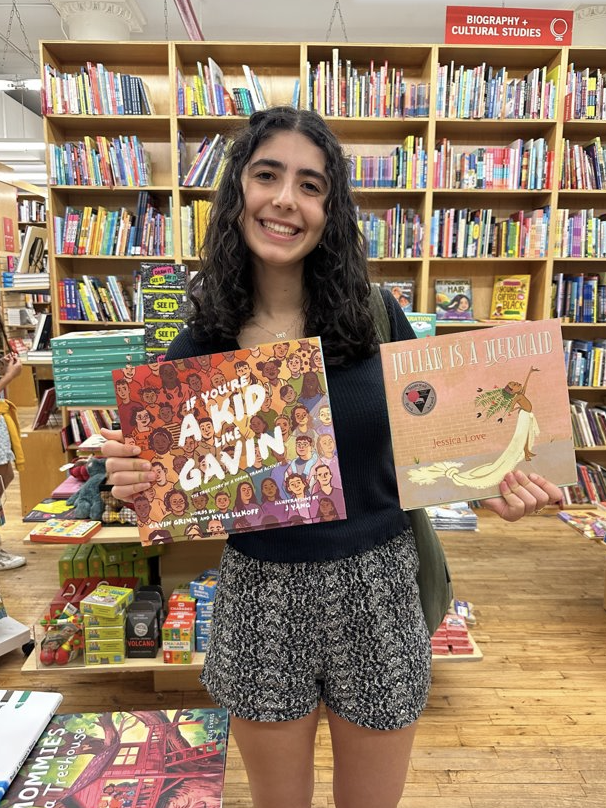 Lori holds up two books in a bookstore.