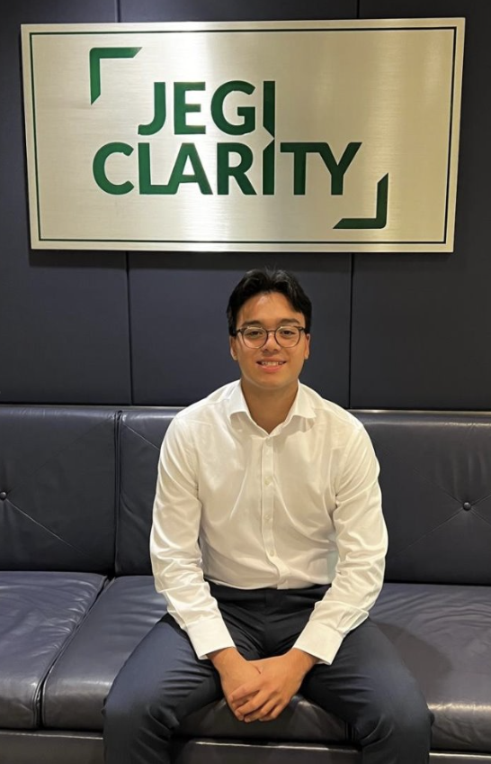 Luc poses in front of JEGI CLARITY's sign