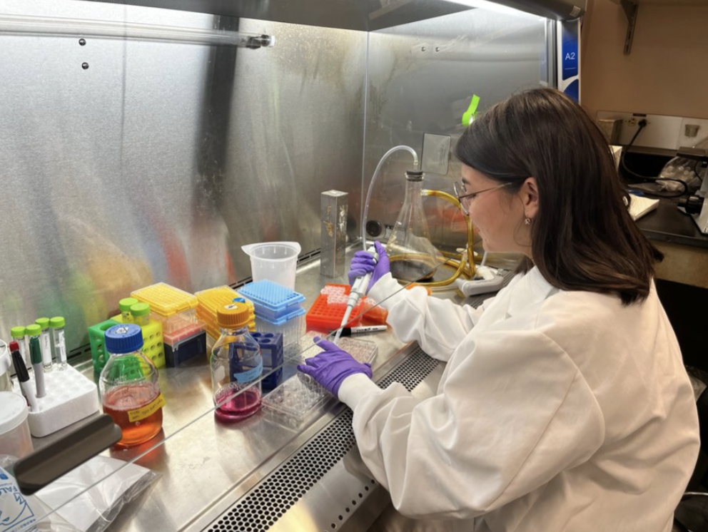 Maryam works at their lab station in a lab coat.