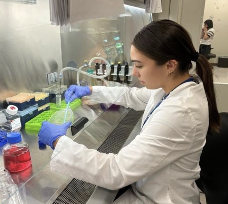 Maya works in the lab, handling various substances and tools.