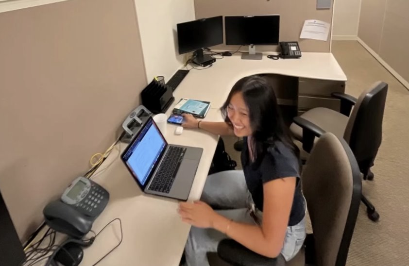 Melissa works on their laptop at their desk at the Boston Medical Center.