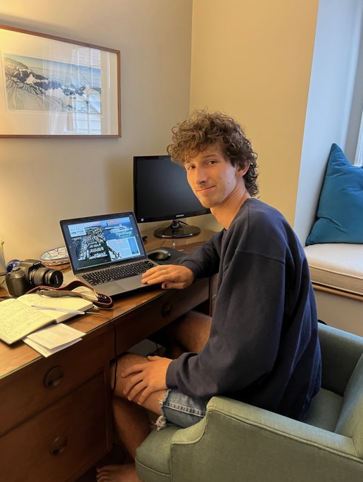 Miles sits at desk working on laptop.
