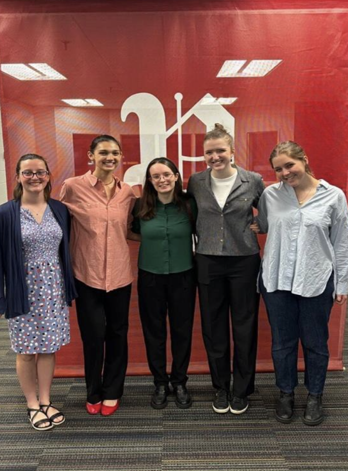 Nikki poses with co-workers in front of the Portland Press Herald's sign. 