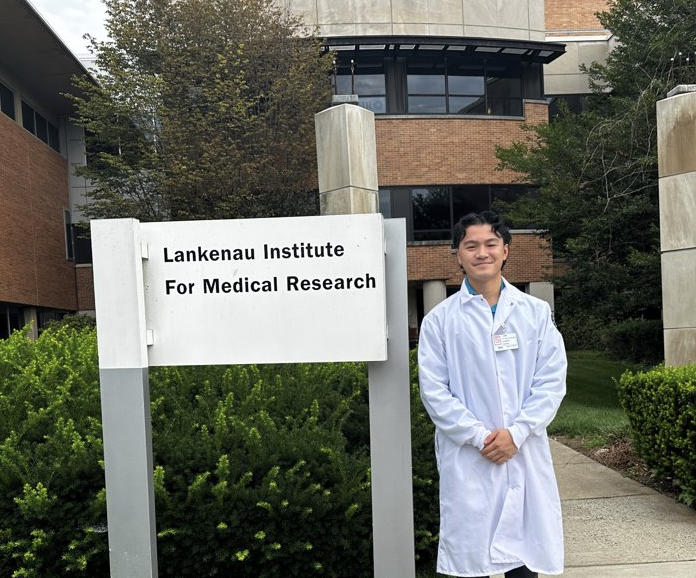 Ryan poses in front of the Lankenau Institute of Medical Research sign.