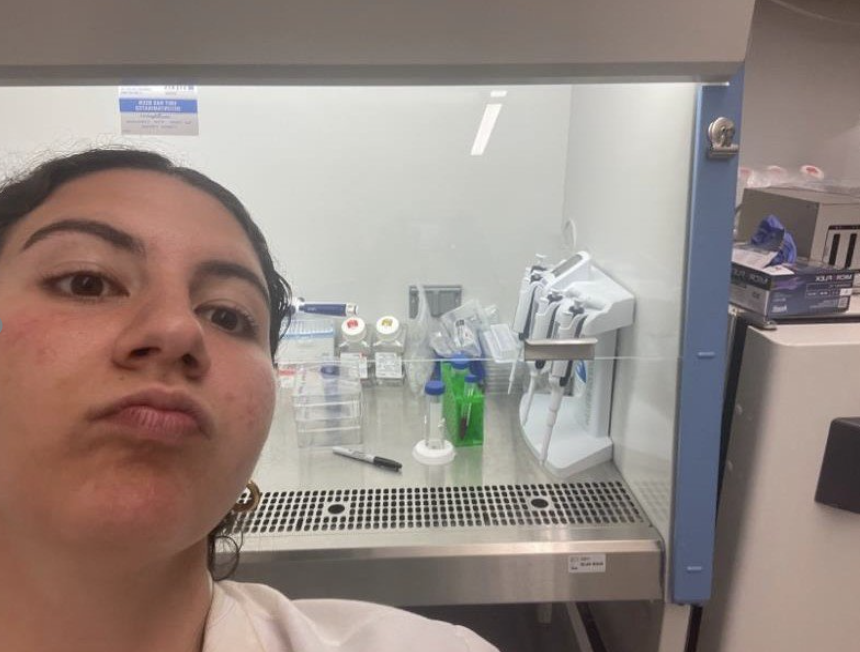 Yasemin poses in front of their laboratory station.