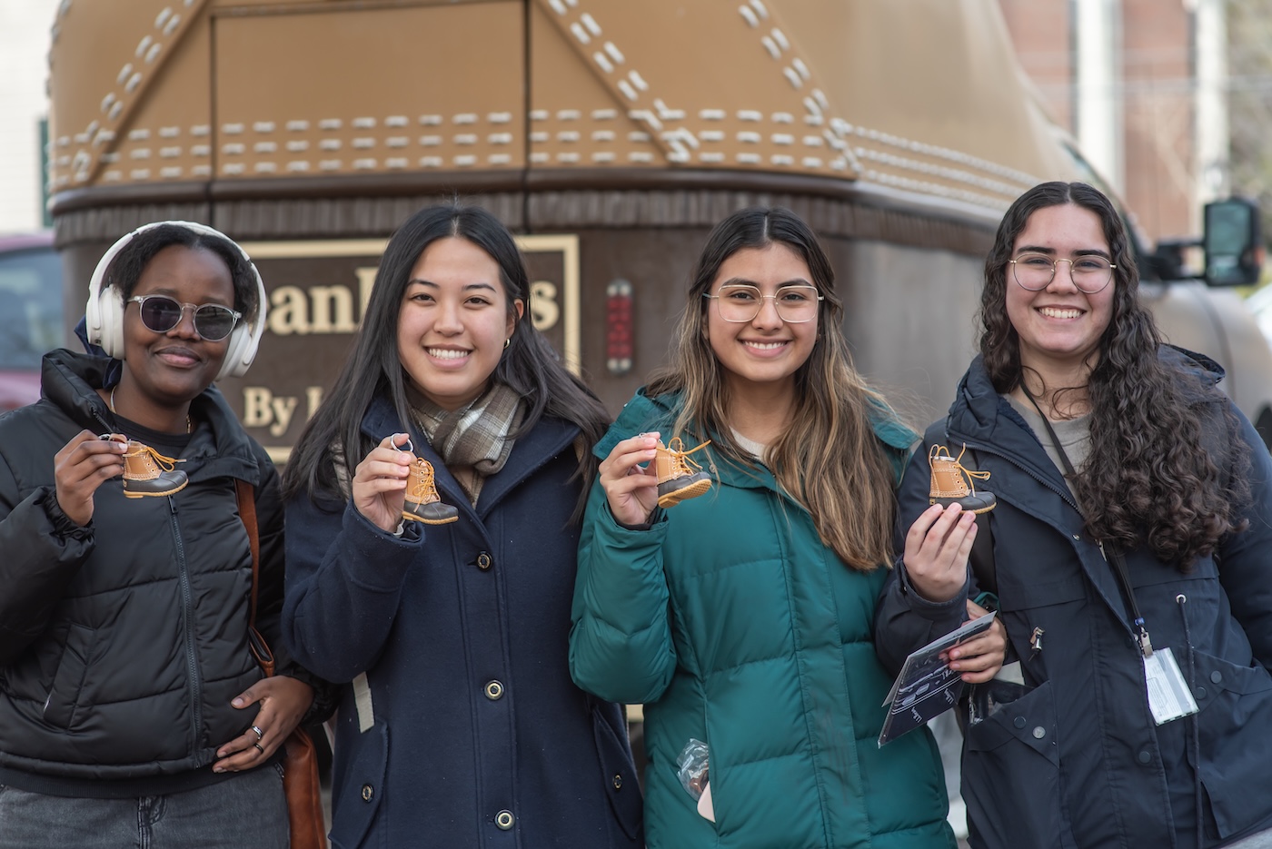 Four students in front of L.L. Bean Bootmobile holding boot keychains
