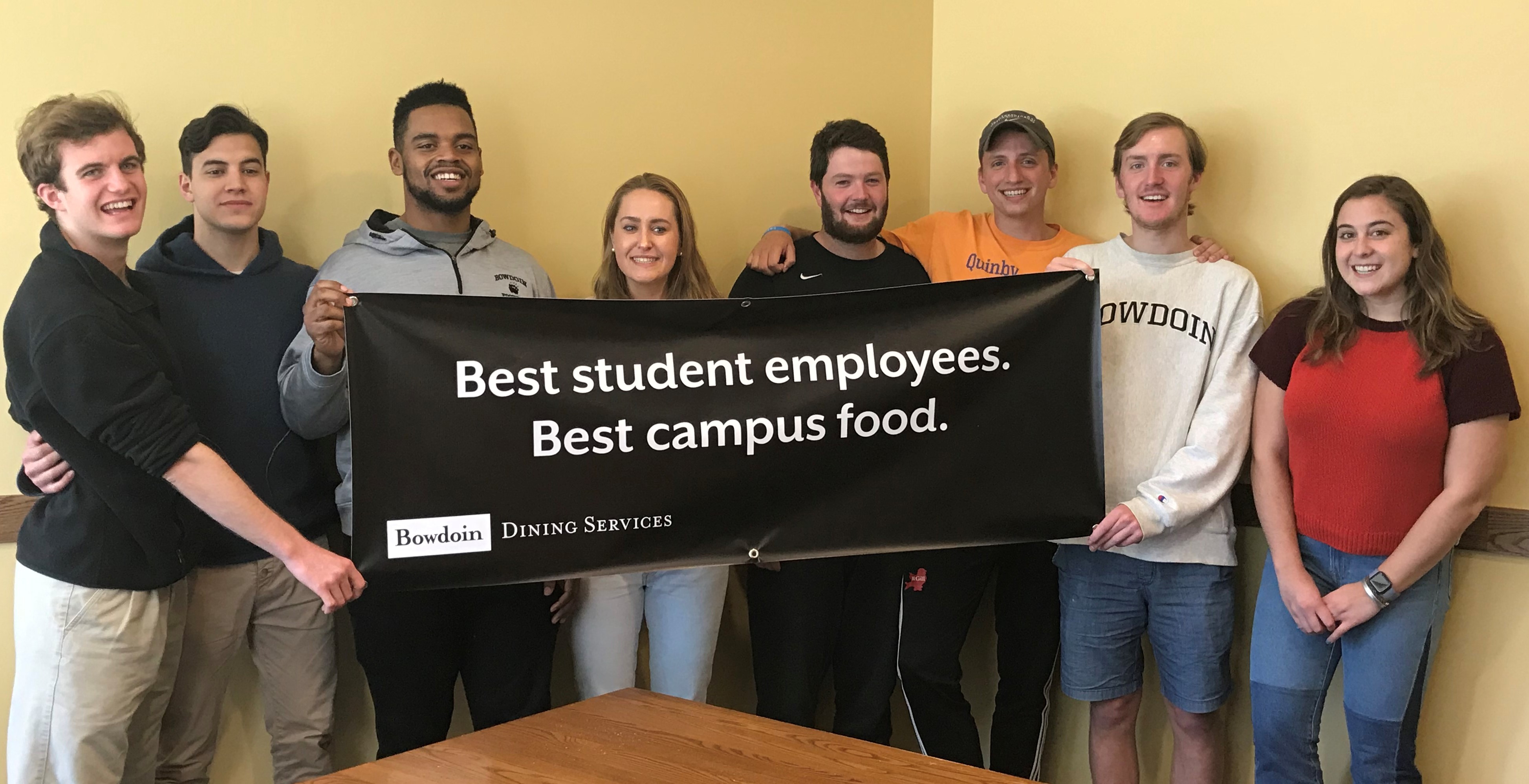 group of student employees holding the sign "best student emplyees, best campus food"