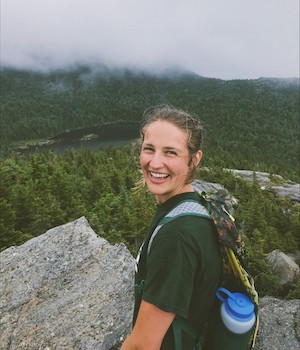 Holly Harris outside and rocks, trees, and skies are behind her