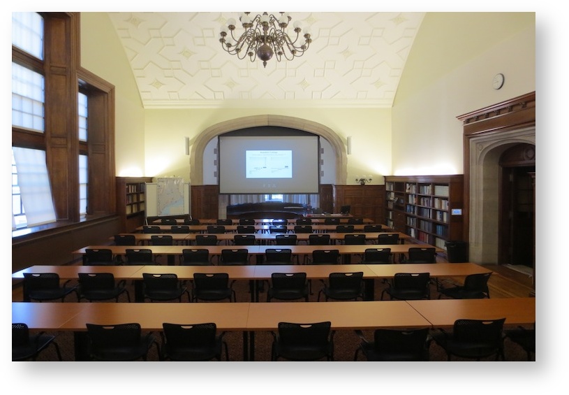 large lecture hall with chairs, tables, projector screen