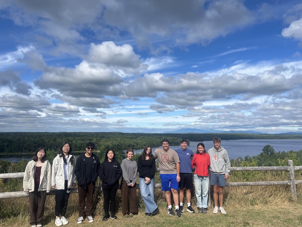 Students leaning against a fence and posing for photo