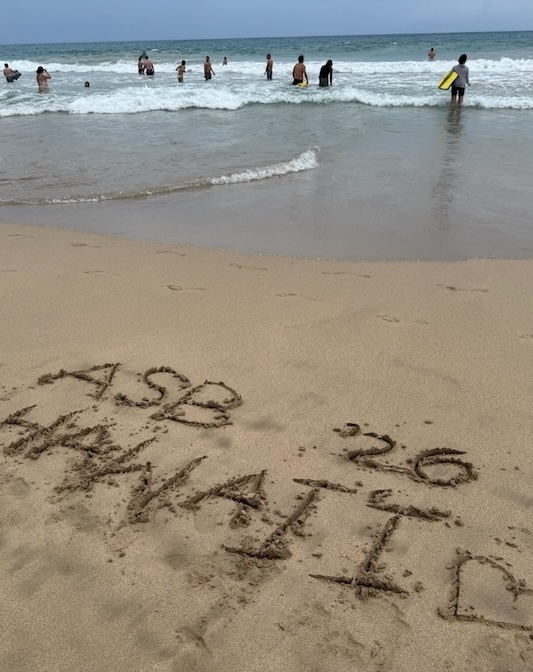 Beach with "ASB '26 Hawai'i" and a heart drawn in the sand