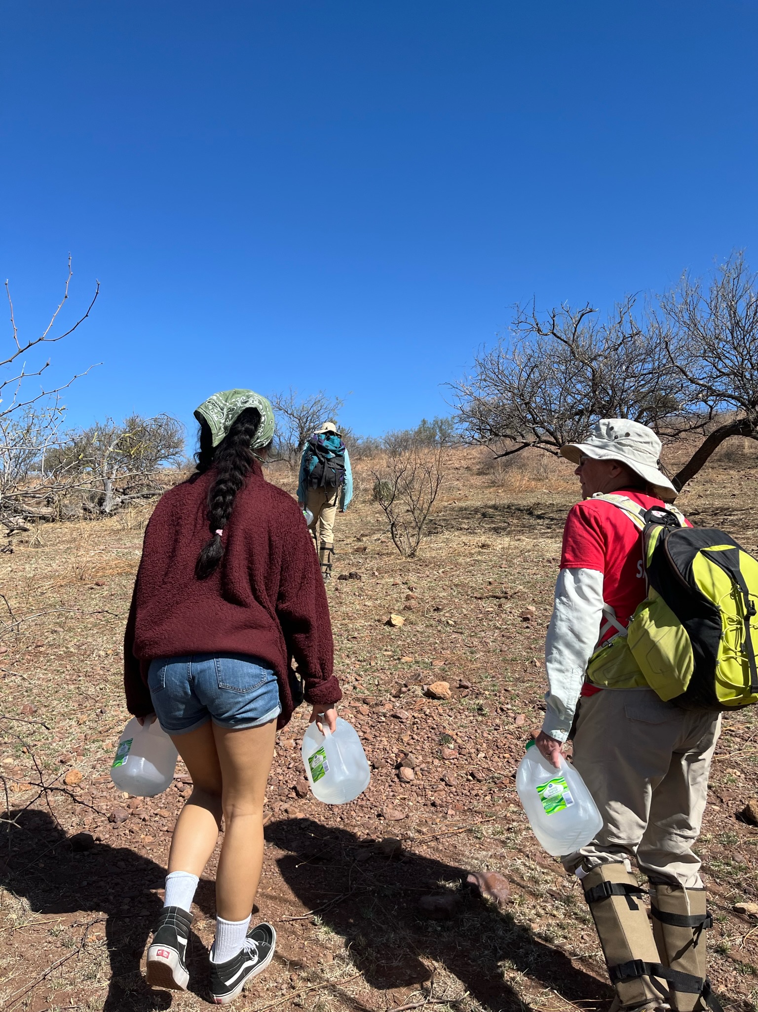 People walking carrying gallons of water